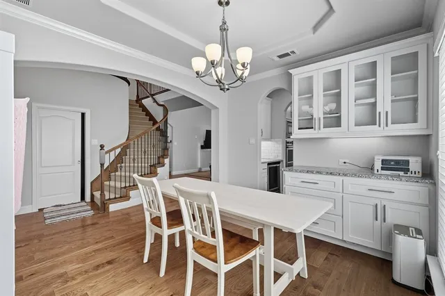 a dining room with wooden floor a chandelier a wooden table and chairs
