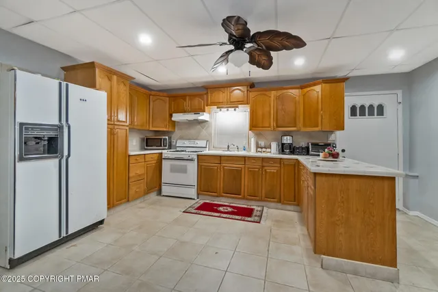 a kitchen with stainless steel appliances granite countertop a refrigerator a sink a stove a washer and a refrigerator