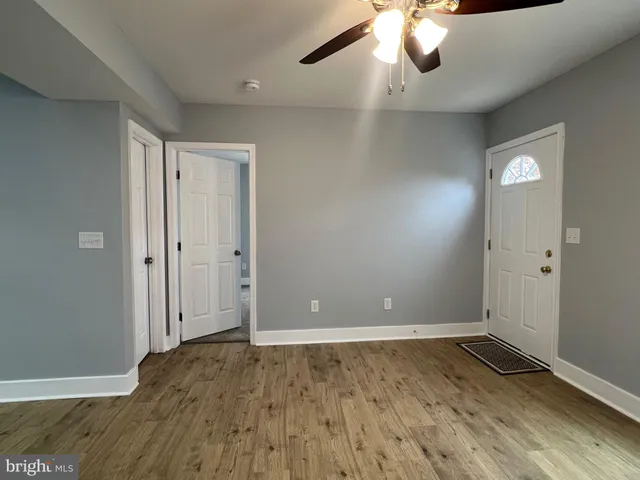 an empty room with ceiling fan and windows