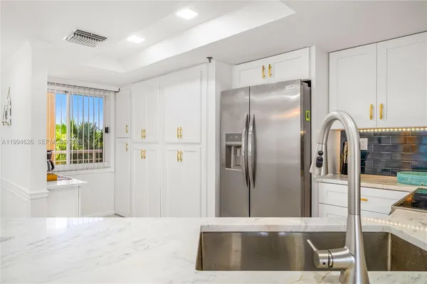 a kitchen with stainless steel appliances kitchen island a refrigerator sink and cabinets
