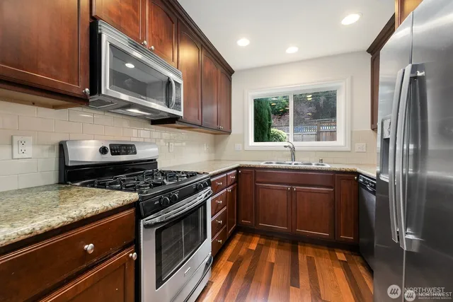 a kitchen with granite countertop wooden cabinets stainless steel appliances and a window