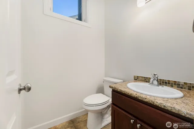 a bathroom with a granite countertop sink and a toilet