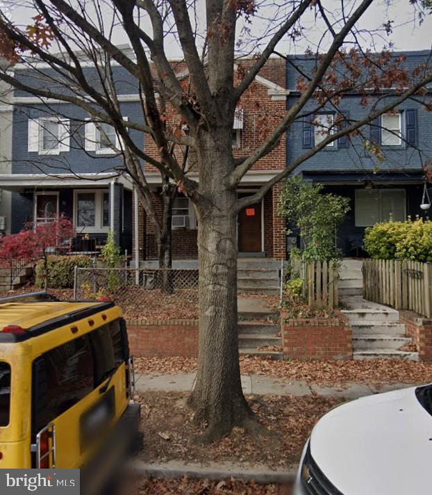 a view of a backyard with table and chairs potted plants and large tree