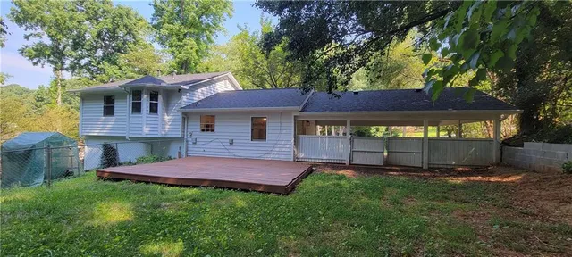 a view of a house with a yard and a large tree
