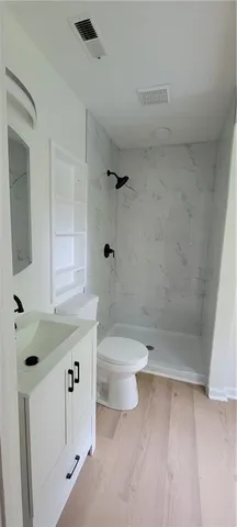 a bathroom with a granite countertop sink a toilet and shower