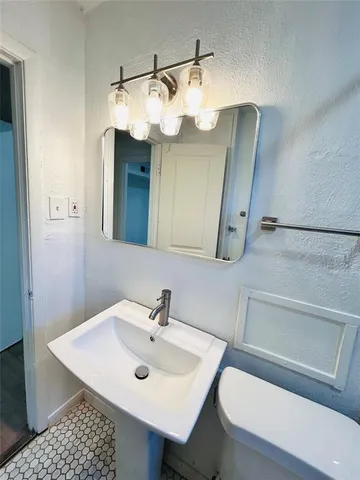 a bathroom with a sink a toilet and mirror