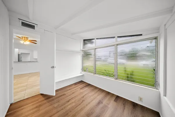 a view of an empty room with wooden floor and a window