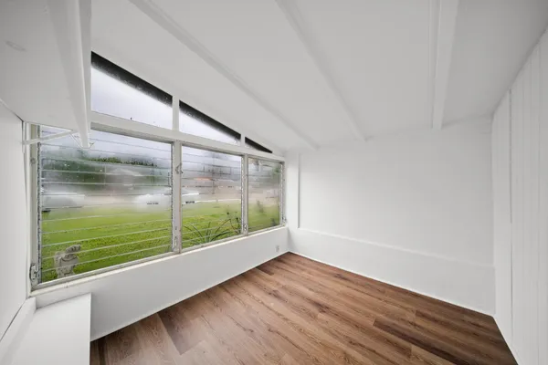 a view of a big room with wooden floor and windows