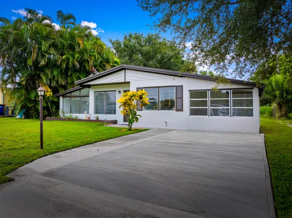 a view of a house with a yard and potted plants