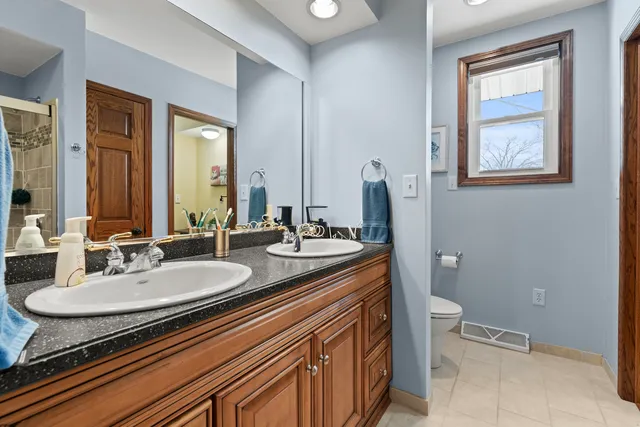 a bathroom with a granite countertop sink mirror vanity and toilet