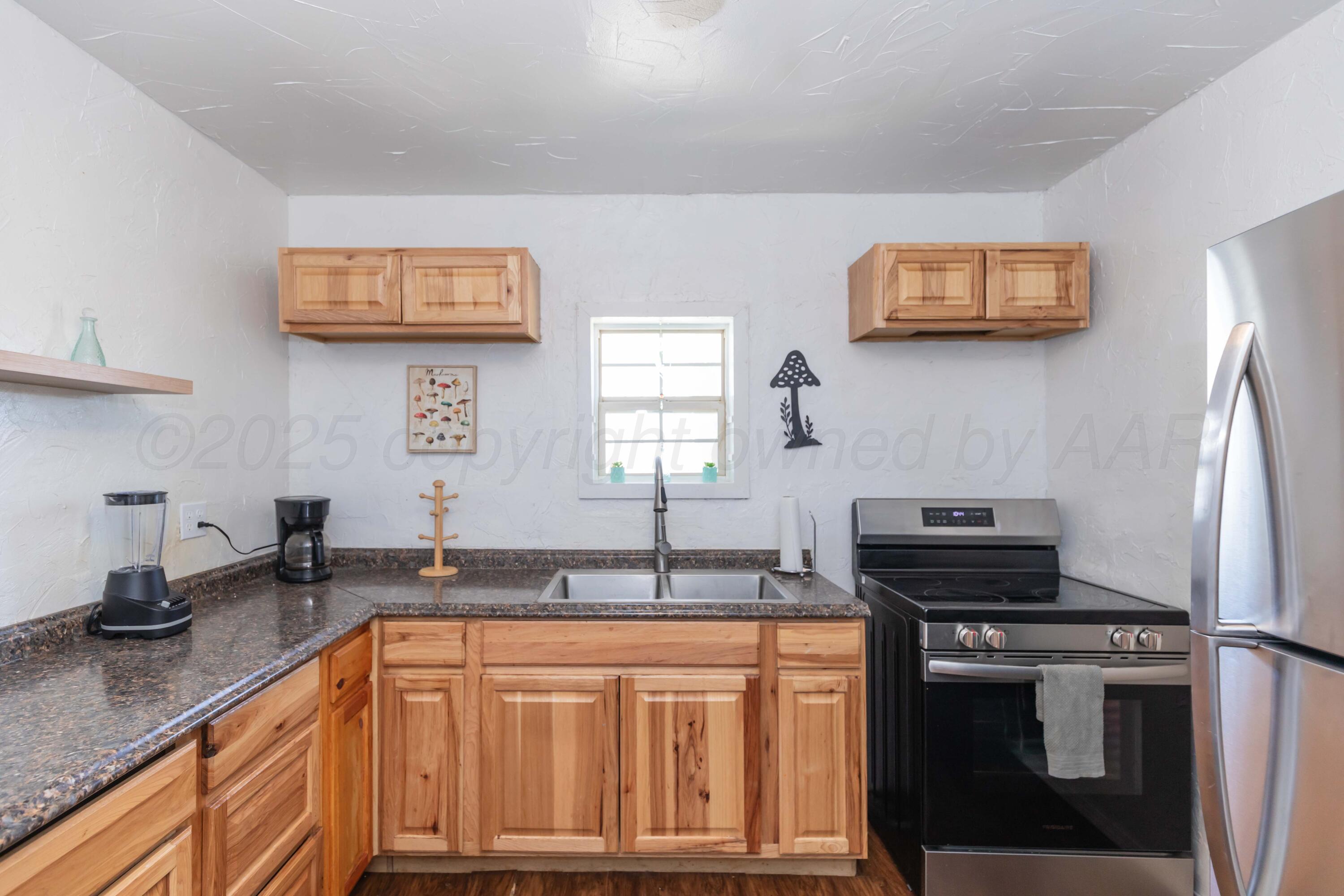 105 Poplar Street Skellytown, TX 79080 - Photo 12 of 37 a kitchen with granite countertop a refrigerator and a sink