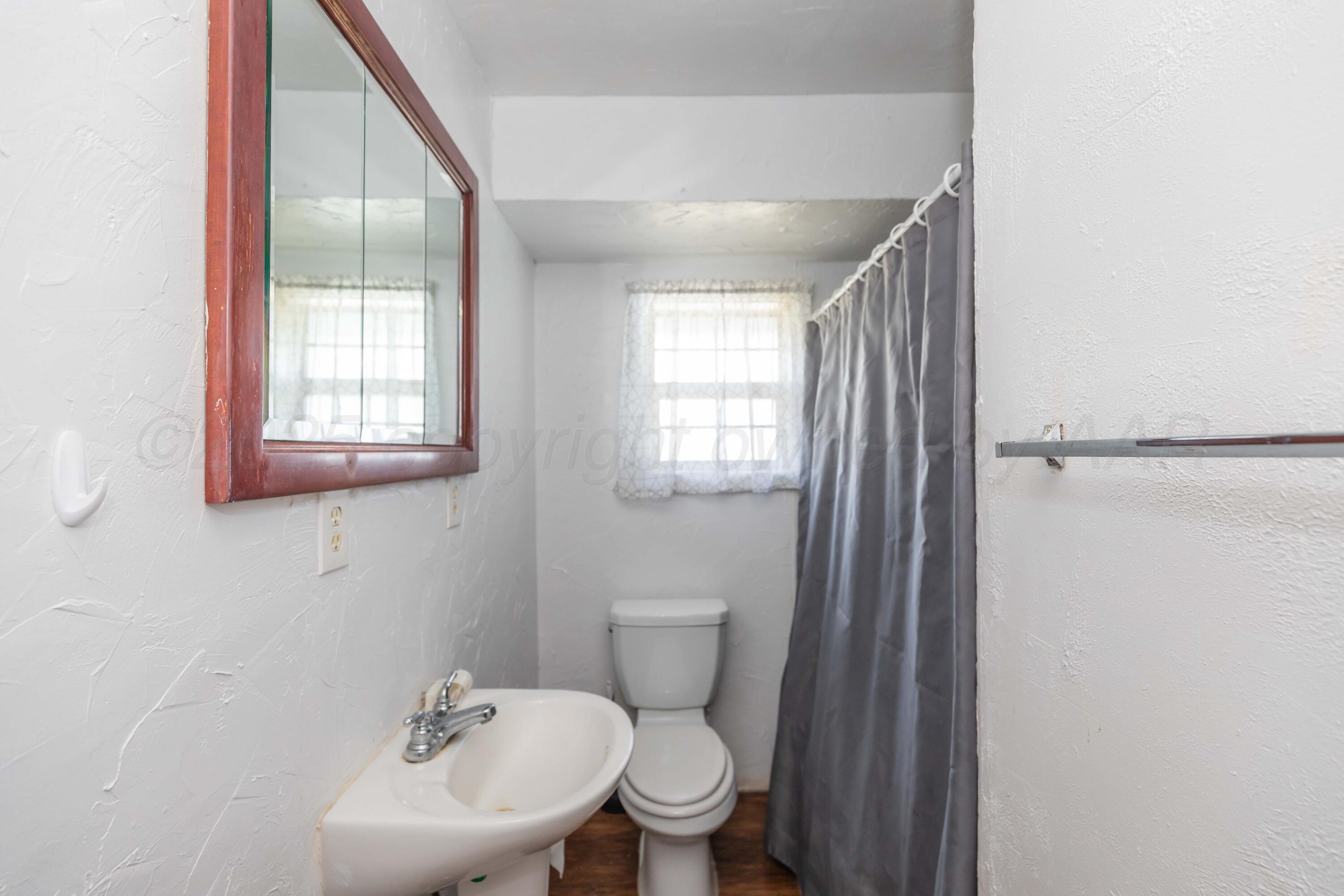 105 Poplar Street Skellytown, TX 79080 - Photo 27 of 37 a bathroom with a toilet a sink and mirror