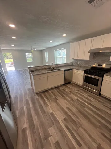 a large kitchen with stainless steel appliances granite countertop a stove a sink dishwasher and a refrigerator