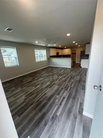 an empty room with wooden floor and windows