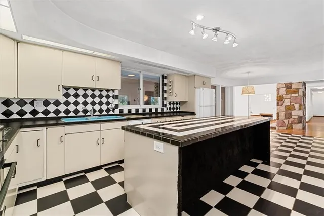 a kitchen with a checkered floor and white cabinets