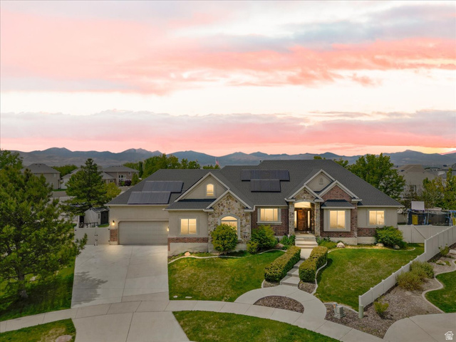Stately residence featuring a stone and brick facade, a multi-car driveway, and mature landscaping