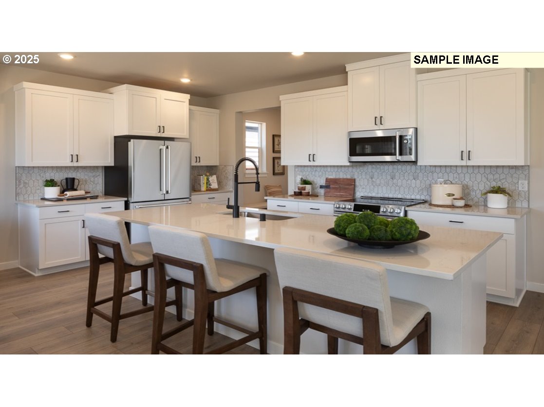 3115 Southwest 4th Avenue Battle Ground, WA 98604 - Photo 4 of 20 a kitchen with stainless steel appliances kitchen island granite countertop a table chairs microwave and sink
