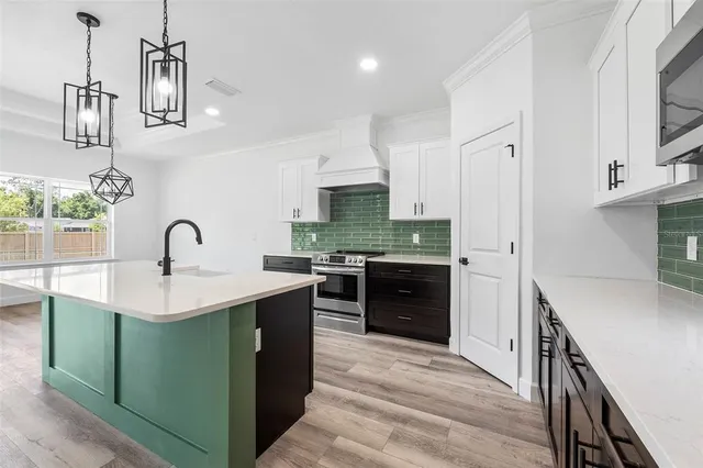 a large kitchen with kitchen island a sink stainless steel appliances and cabinets
