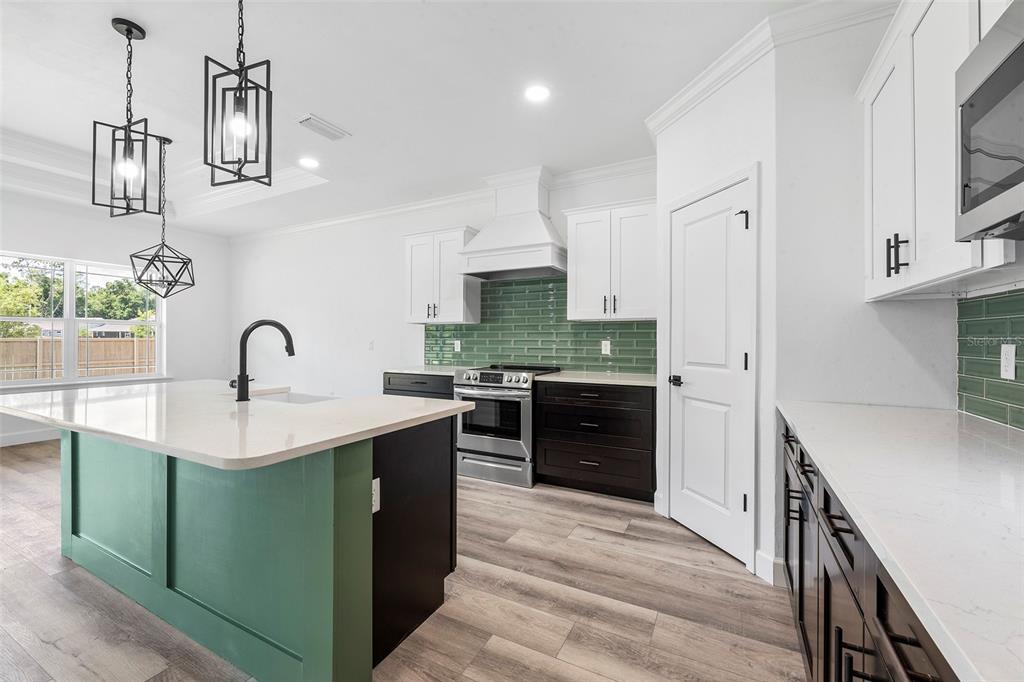 6723 Southwest 15 Place Gainesville, FL 32607 - Photo 9 of 24 a kitchen with kitchen island stainless steel appliances a sink stove and refrigerator
