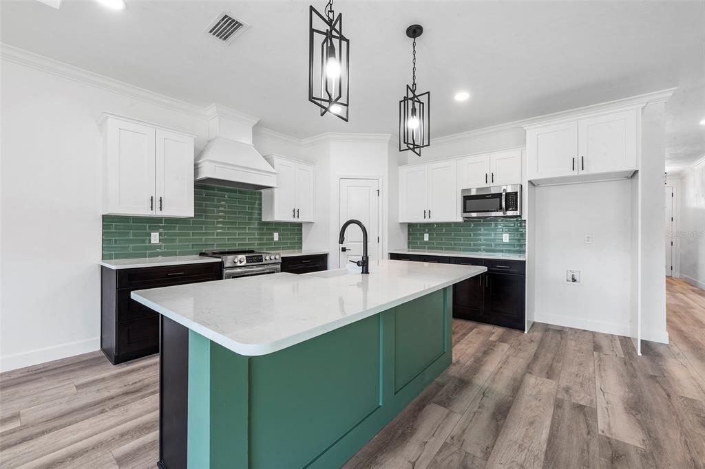 6723 Southwest 15 Place Gainesville, FL 32607 - Photo 10 of 24 a large kitchen with kitchen island a sink stainless steel appliances and cabinets