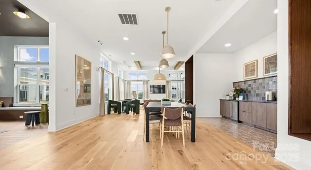 a open kitchen with stainless steel appliances granite countertop a stove a refrigerator a kitchen island a dining table and chairs with wooden floor