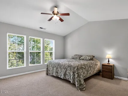 a bed sitting in a spacious bedroom next to a window