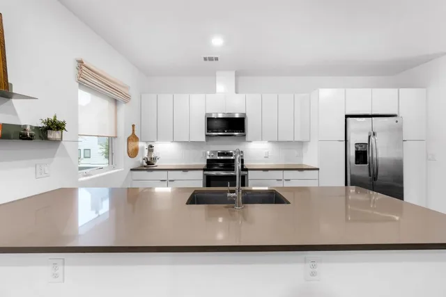 a kitchen with kitchen island a counter top a stove a sink and a refrigerator