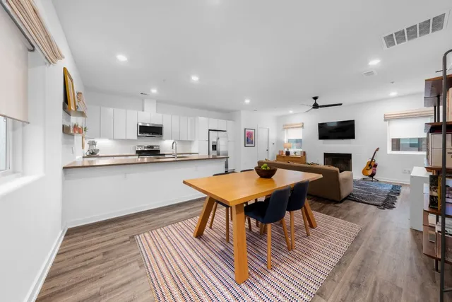 a kitchen with stainless steel appliances a stove a sink a microwave a refrigerator and white cabinets with wooden floor