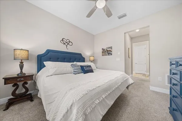 a bedroom with a bed a mirror on dresser and a chandelier