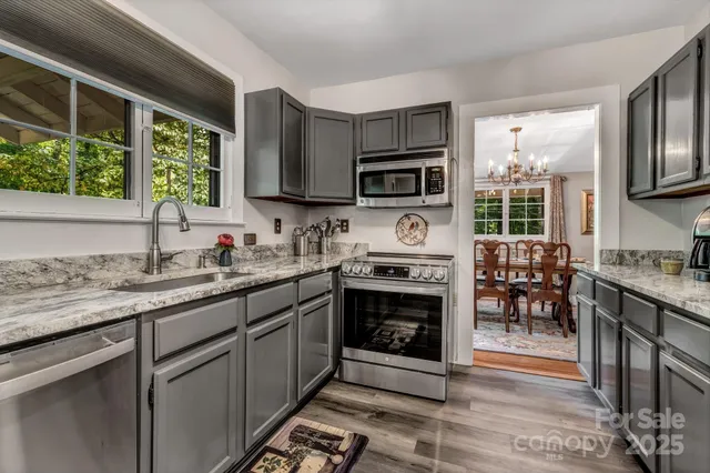a kitchen with stainless steel appliances granite countertop a stove a sink and a microwave
