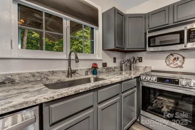 a kitchen with stainless steel appliances granite countertop a stove a sink and a microwave