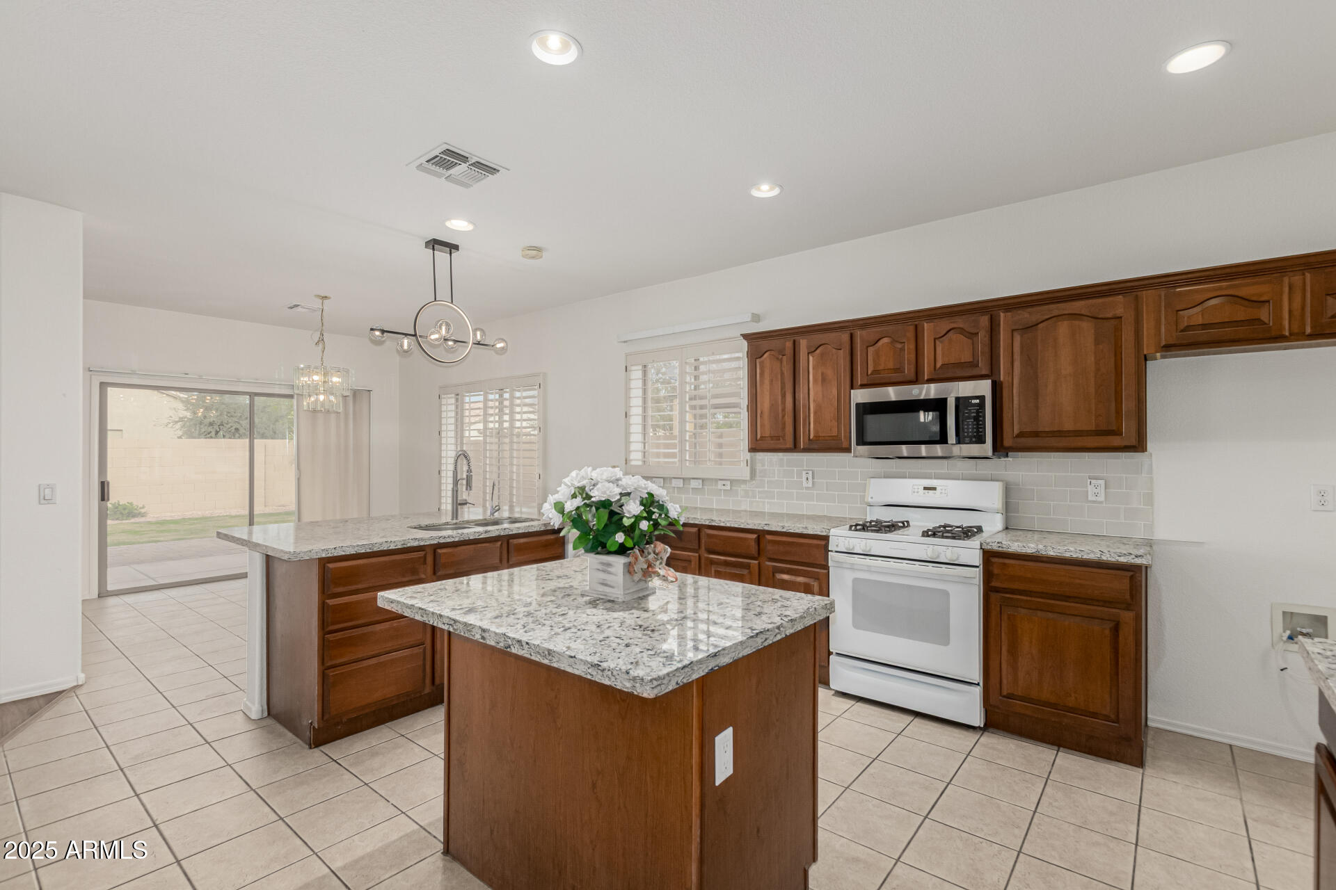 2978 East Ranch Court Gilbert, AZ 85296 - Photo 14 of 72 a kitchen with stainless steel appliances kitchen island granite countertop a refrigerator a stove top oven a sink dishwasher and white cabinets with wooden floor
