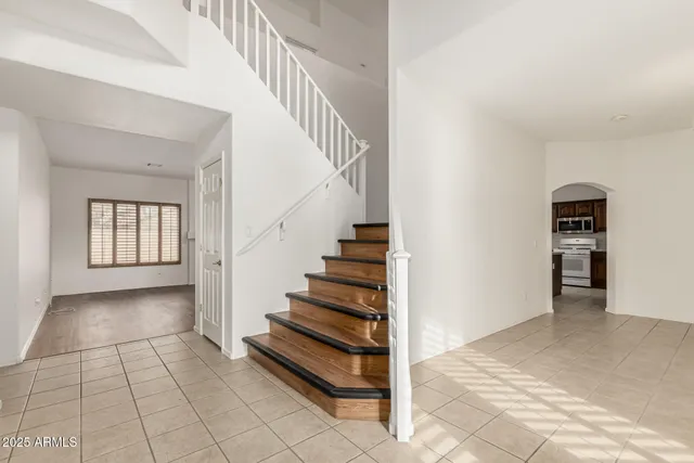 a view of an empty room with wooden floor and a ceiling fan