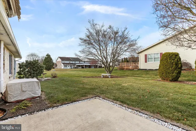 a view of a white house next to a yard with big trees