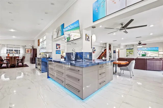 a kitchen with stainless steel appliances kitchen island granite countertop a refrigerator a stove top oven a sink dishwasher and white cabinets next to a window