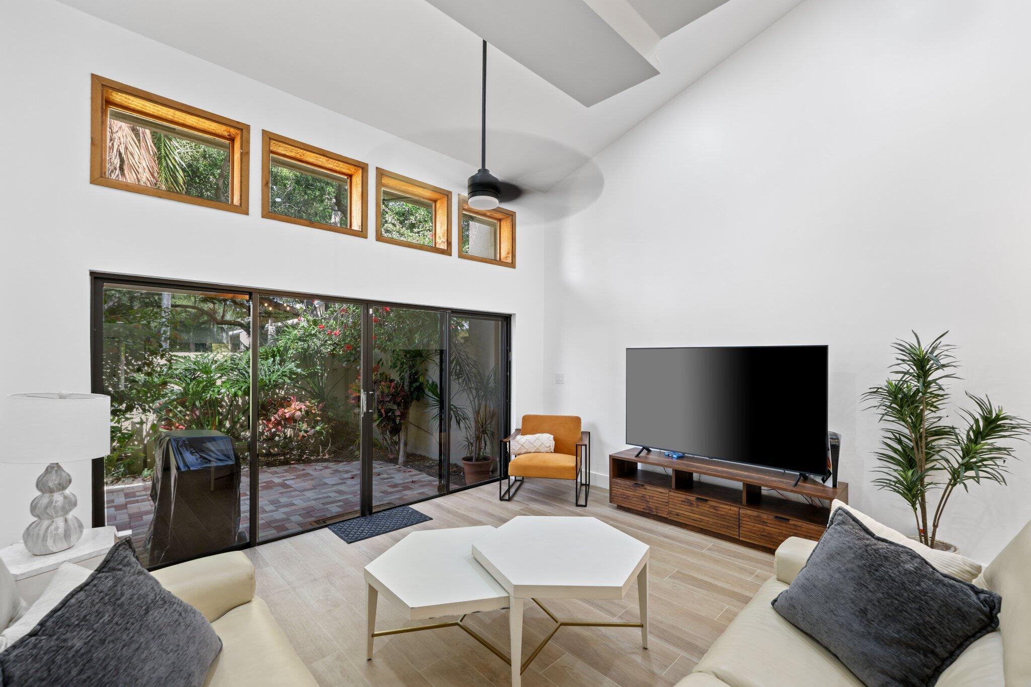 1400 Northwest 9th Avenue, Unit E34 Boca Raton, FL 33486 - Photo 15 of 46 a living room with furniture a flat screen tv and a floor to ceiling window