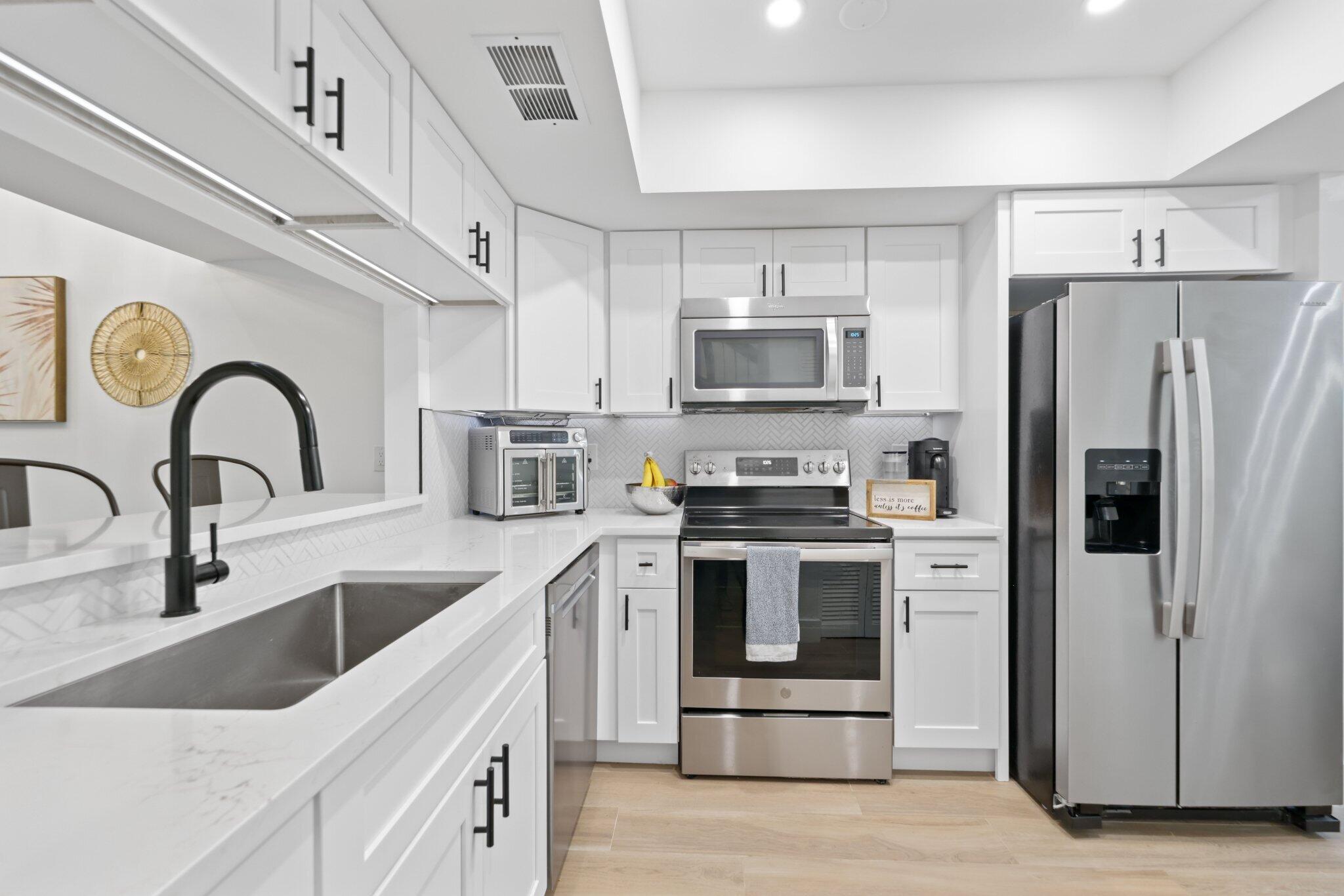 1400 Northwest 9th Avenue, Unit E34 Boca Raton, FL 33486 - Photo 4 of 46 a kitchen with stainless steel appliances granite countertop a sink stove and refrigerator