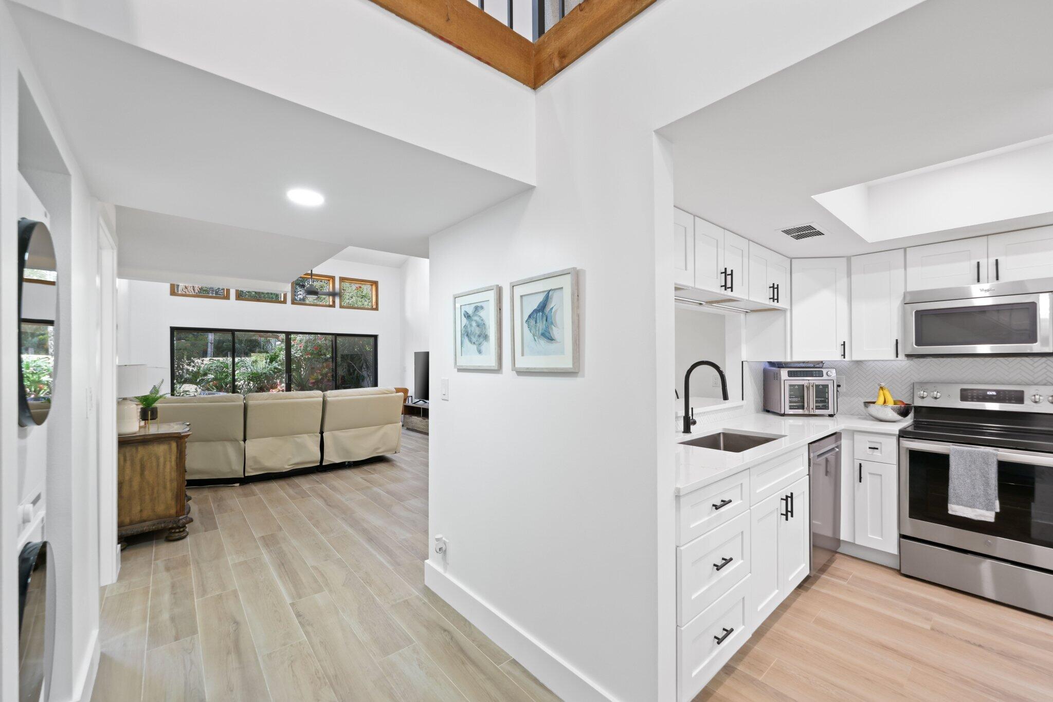 1400 Northwest 9th Avenue, Unit E34 Boca Raton, FL 33486 - Photo 10 of 46 a kitchen with stainless steel appliances a stove a sink dishwasher a refrigerator and white cabinets with wooden floor