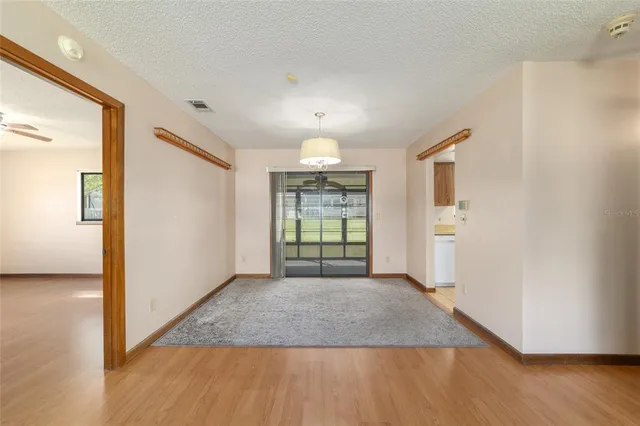 an empty room with wooden floor cabinet and windows