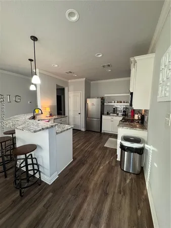 a kitchen with stainless steel appliances kitchen island granite countertop a refrigerator a stove a sink dishwasher and a dining table with wooden floor