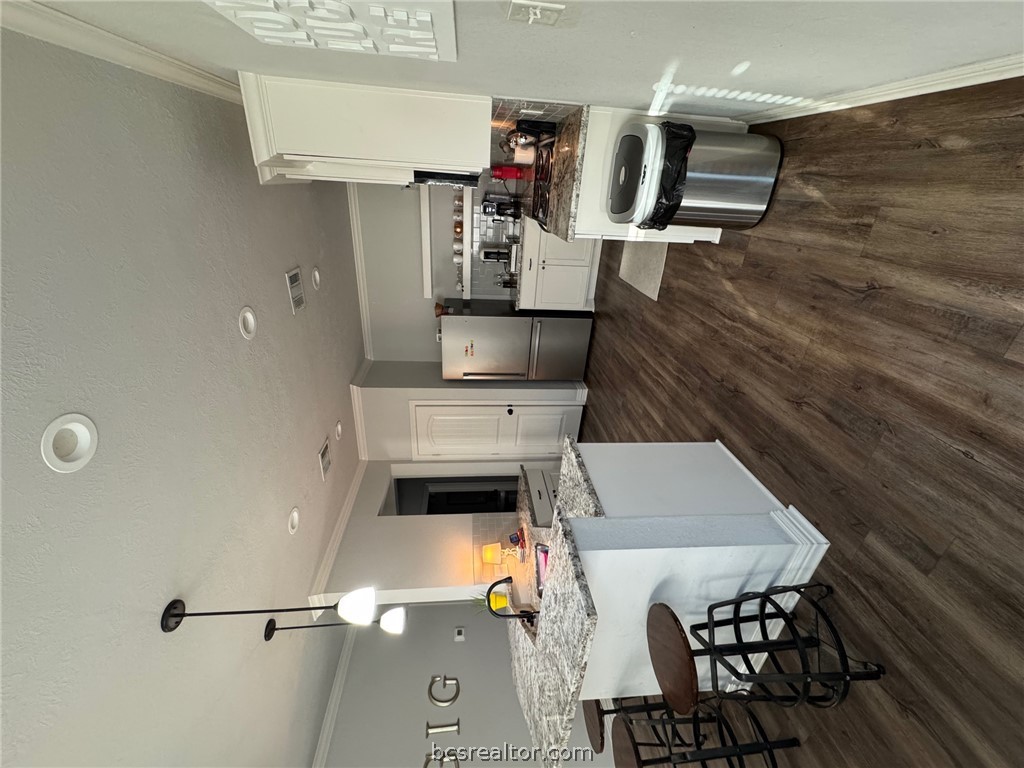 6991 Halter Loop College Station, TX 77845 - Photo 4 of 10 a kitchen with stainless steel appliances kitchen island granite countertop a refrigerator a stove a sink dishwasher and a dining table with wooden floor