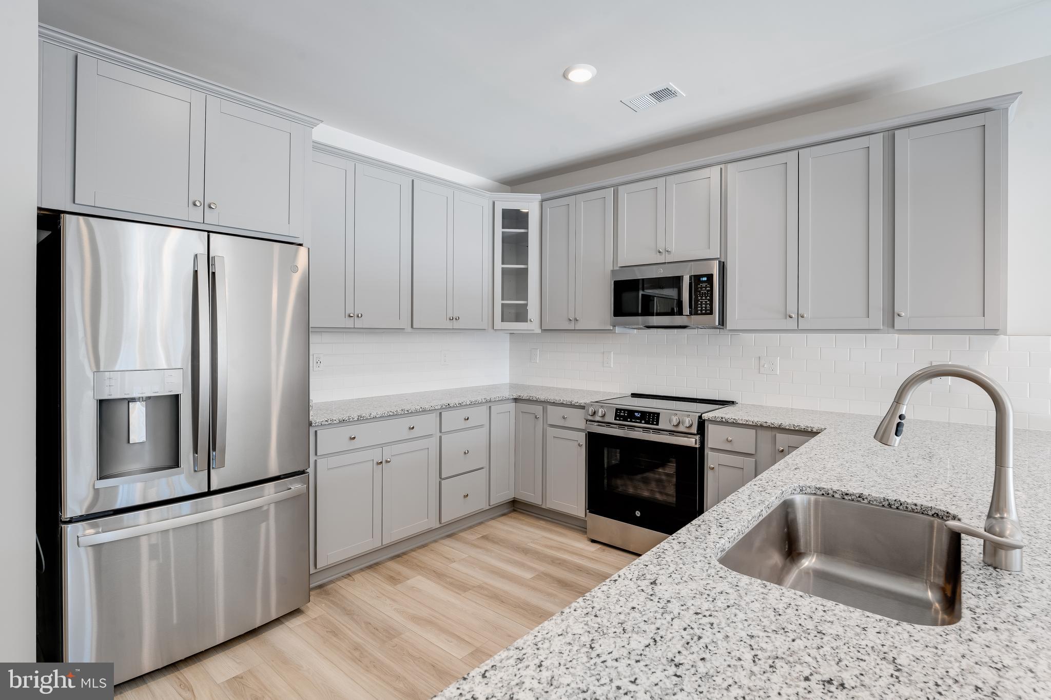 4005 Seaside Alder Road, Unit D Bowie, MD 20720 - Photo 11 of 19 a kitchen with granite countertop a refrigerator stove and microwave
