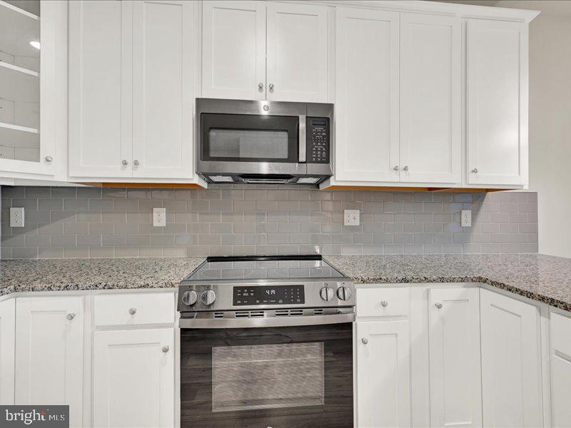 4005 Seaside Alder Road, Unit D Bowie, MD 20720 - Photo 14 of 41 a kitchen with granite countertop white cabinets and a stove top oven