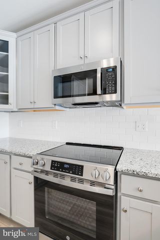 a kitchen with granite countertop white cabinets and stainless steel appliances