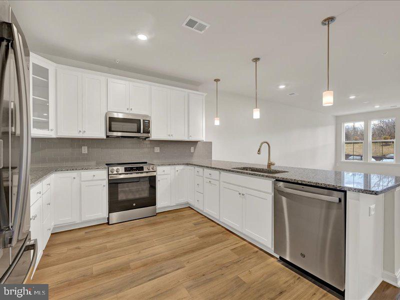4005 Seaside Alder Road, Unit D Bowie, MD 20720 - Photo 6 of 41 a kitchen with stainless steel appliances granite countertop a sink a stove a refrigerator and cabinets with wooden floor