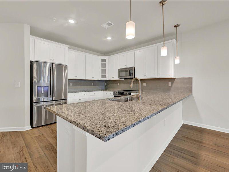 4005 Seaside Alder Road, Unit D Bowie, MD 20720 - Photo 9 of 41 a kitchen with kitchen island granite countertop a sink refrigerator and microwave
