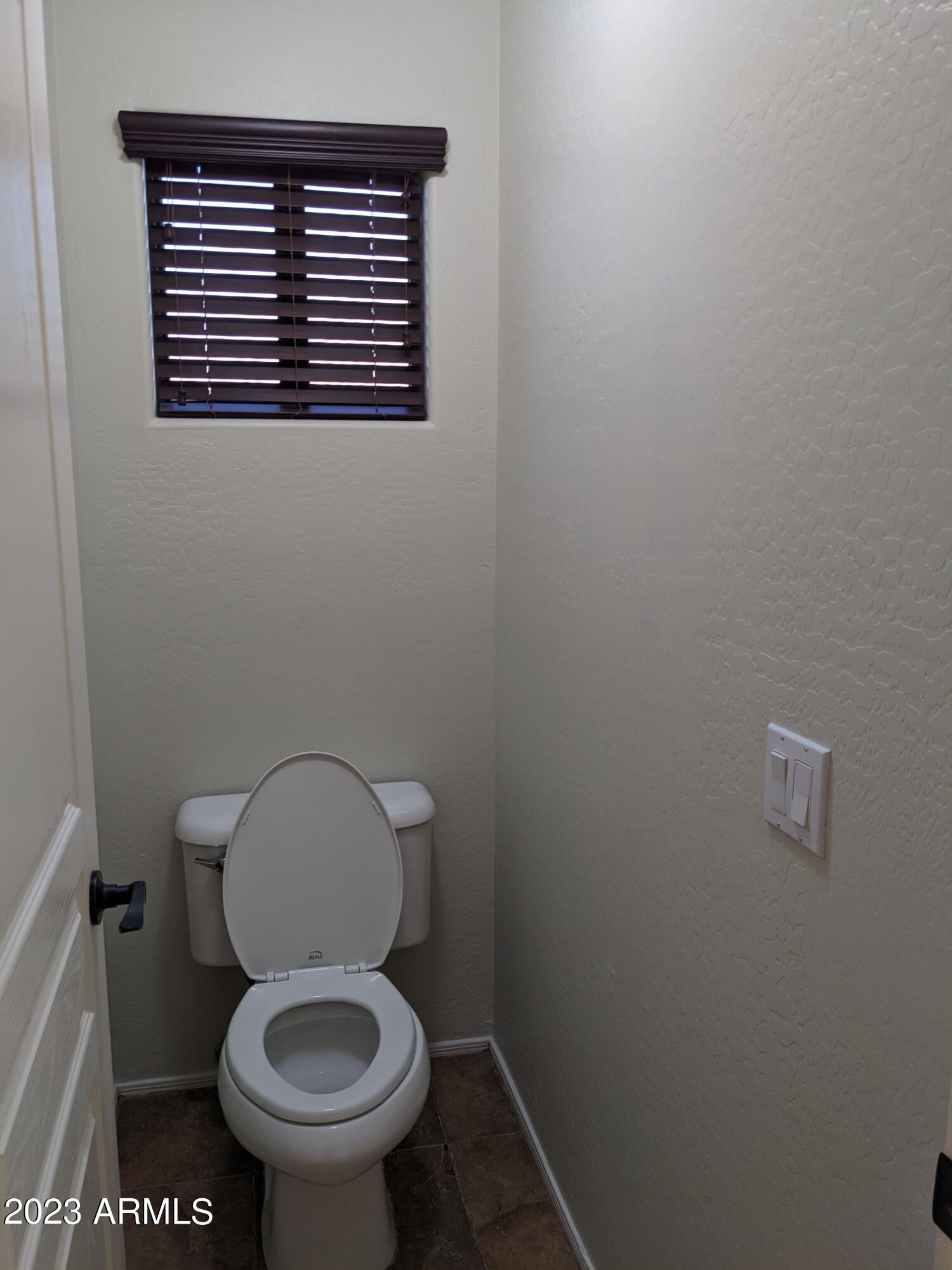 14099 West Riviera Drive Surprise, AZ 85379 - Photo 20 of 27 a white toilet sitting in a bathroom next to a wooden wall