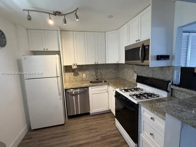 a kitchen with stainless steel appliances granite countertop a refrigerator stove a sink and a microwave