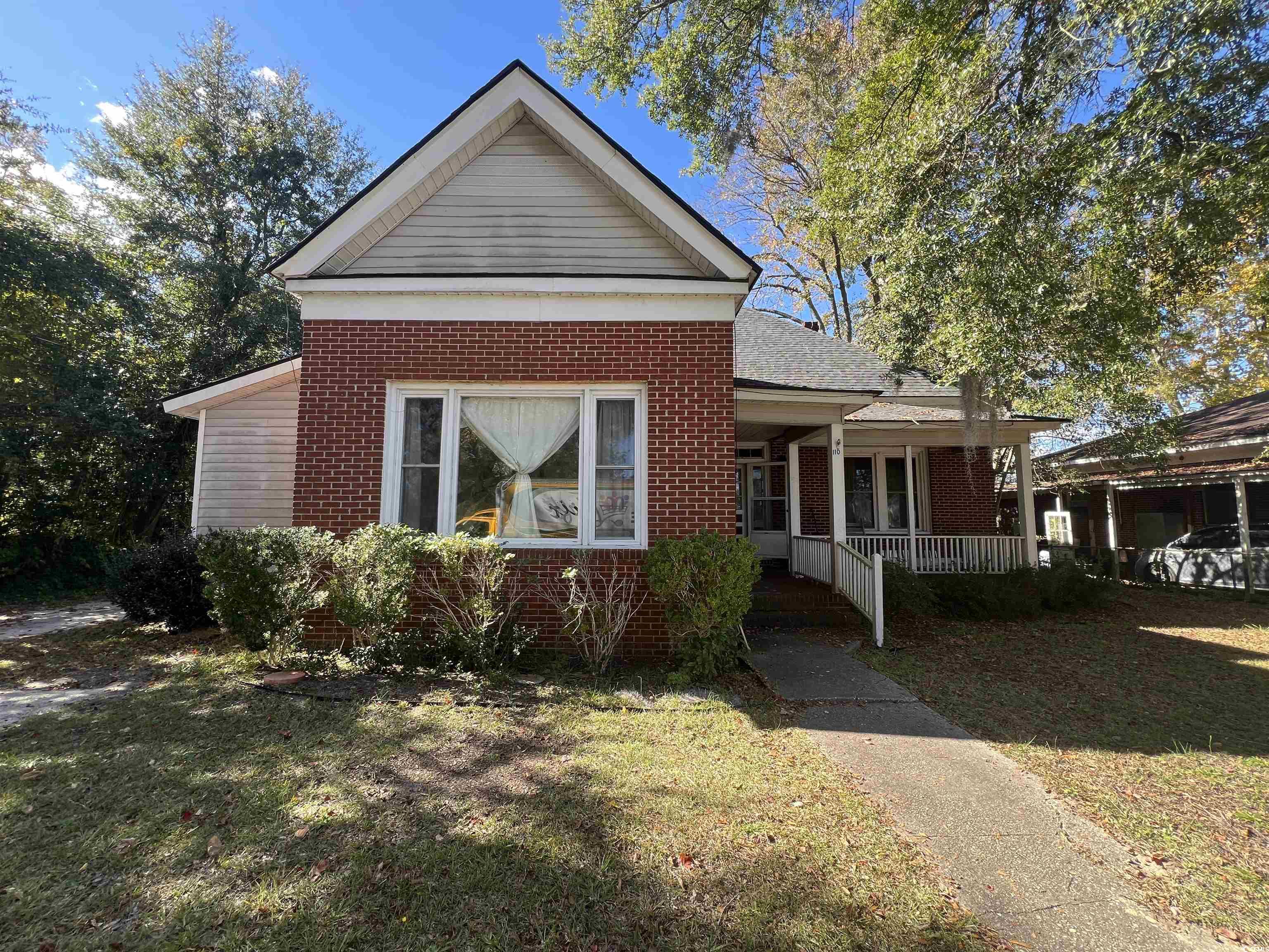 Bungalow-style home with a porch, a front yard, and brick siding