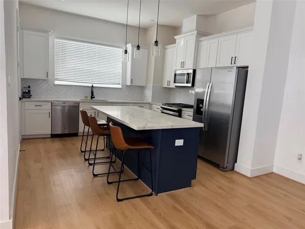a kitchen with stainless steel appliances granite countertop a refrigerator a sink dishwasher a stove with wooden cabinets and wooden floor